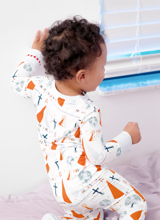 Baby boy playing on bed in Divine Mercy footie pajamas