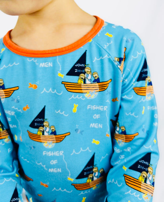 Boy wearing Catholic pajamas with Jesus, boat, and fisherman pattern on a blue background