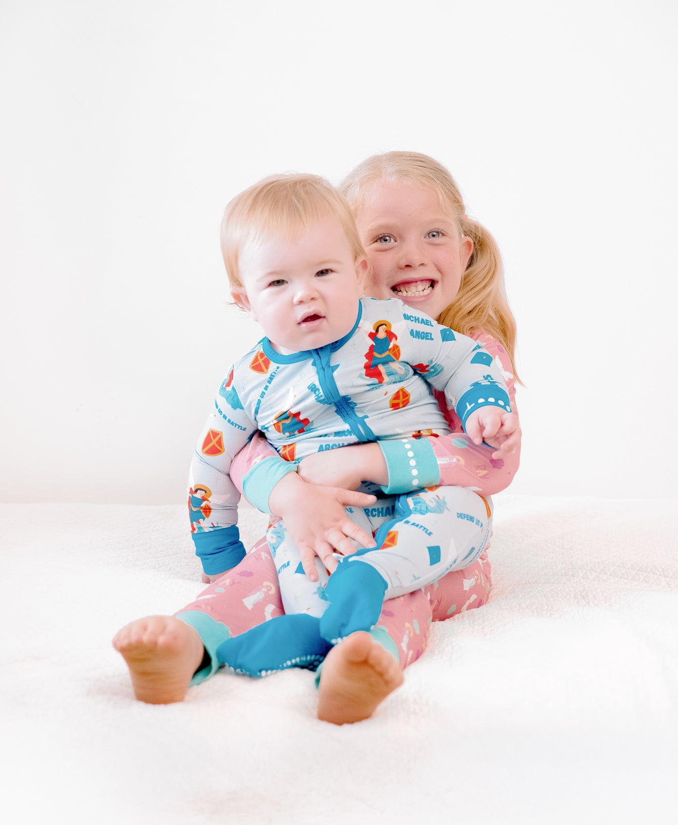 Baby boy and big sister wearing Catholic kids pajamas