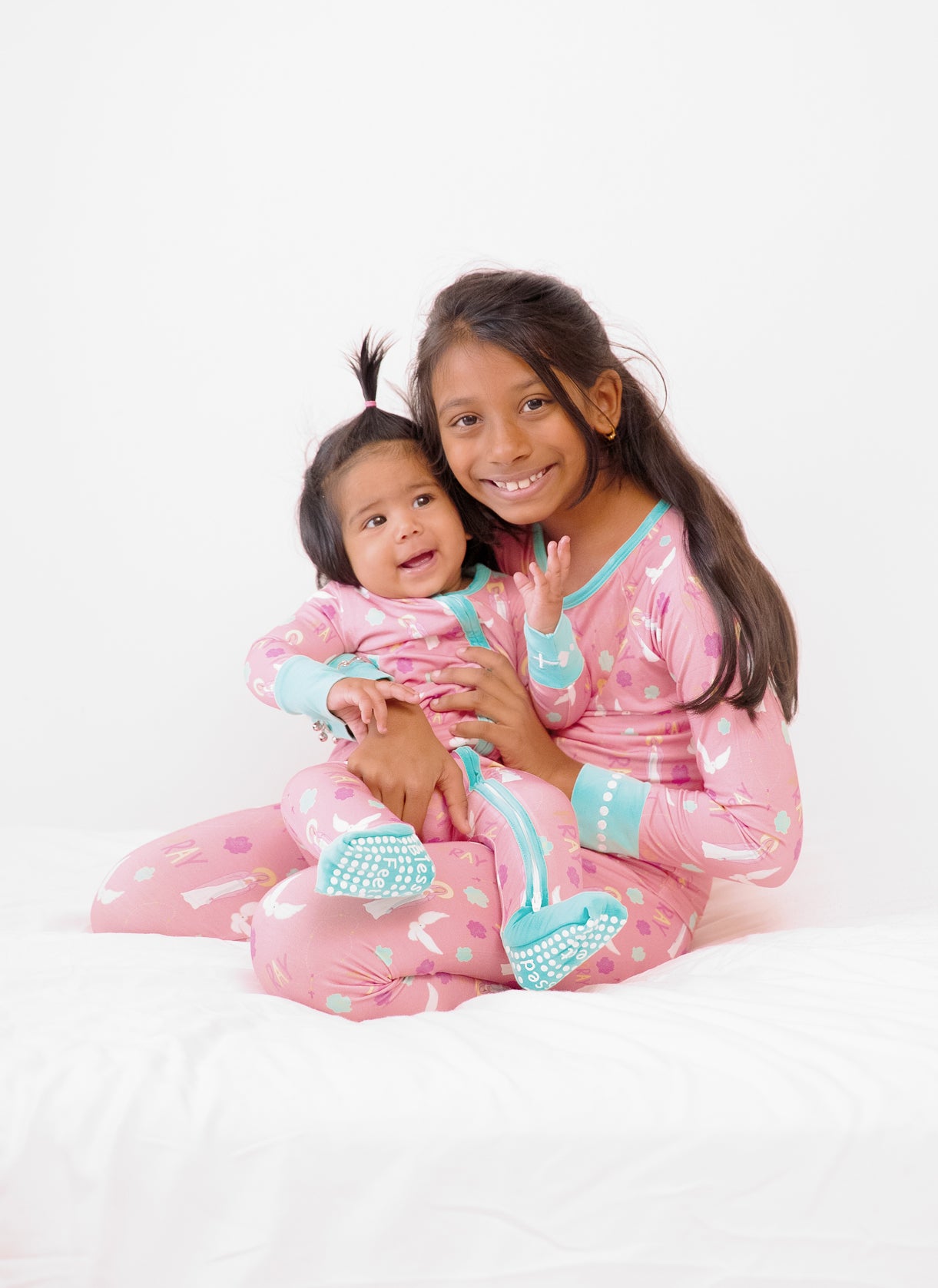 Two girls wearing matching Catholic pajamas with Pray theme