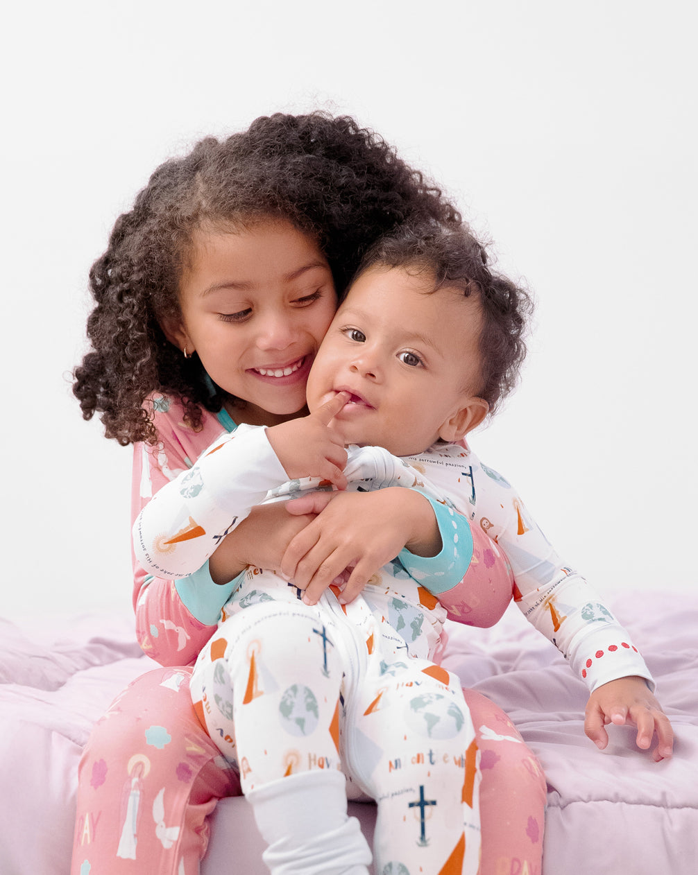 Girl holding baby boy wearing Divine Mercy pajamas