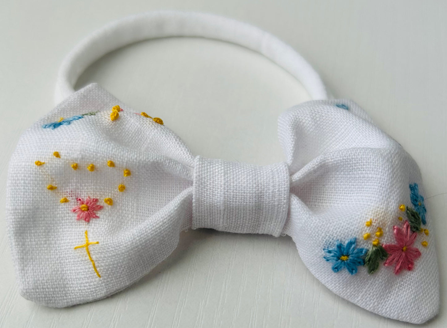 White linen baby bow with Catholic hand-embroidered accents