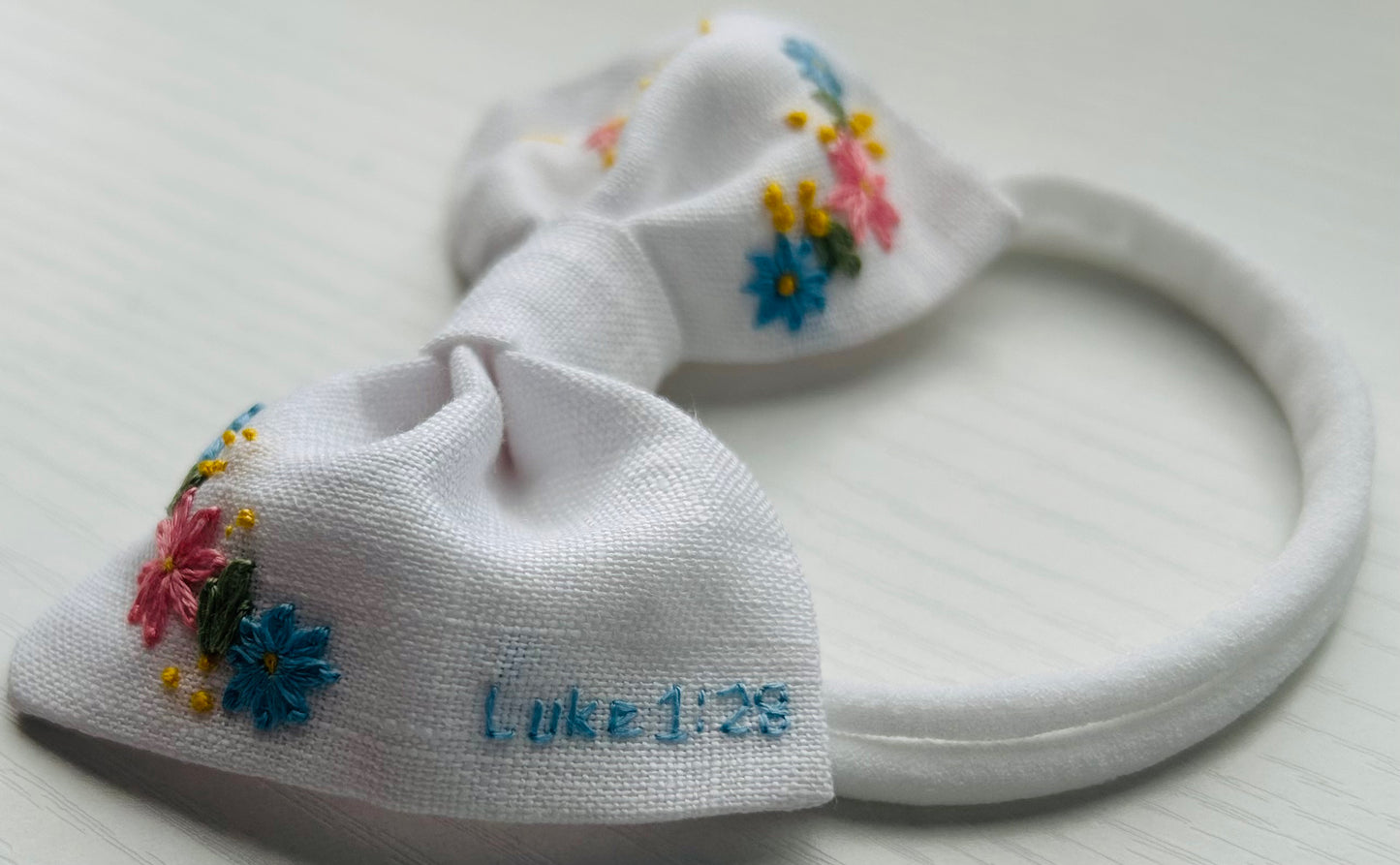 White linen baby bow with Catholic hand-embroidered accents