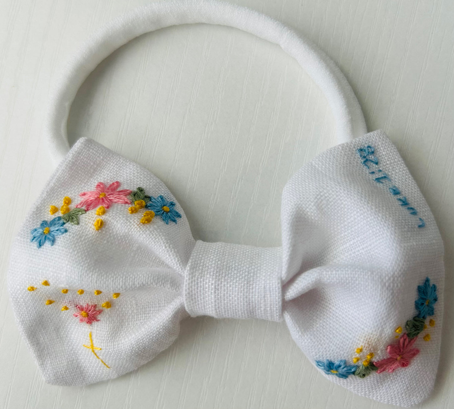 White linen baby bow with Catholic hand-embroidered accents