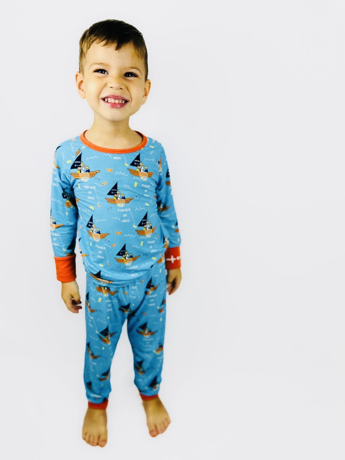 Boy wearing Catholic kids pajamas with disciples in boat with Jesus design and embroidered rosary wrist detail